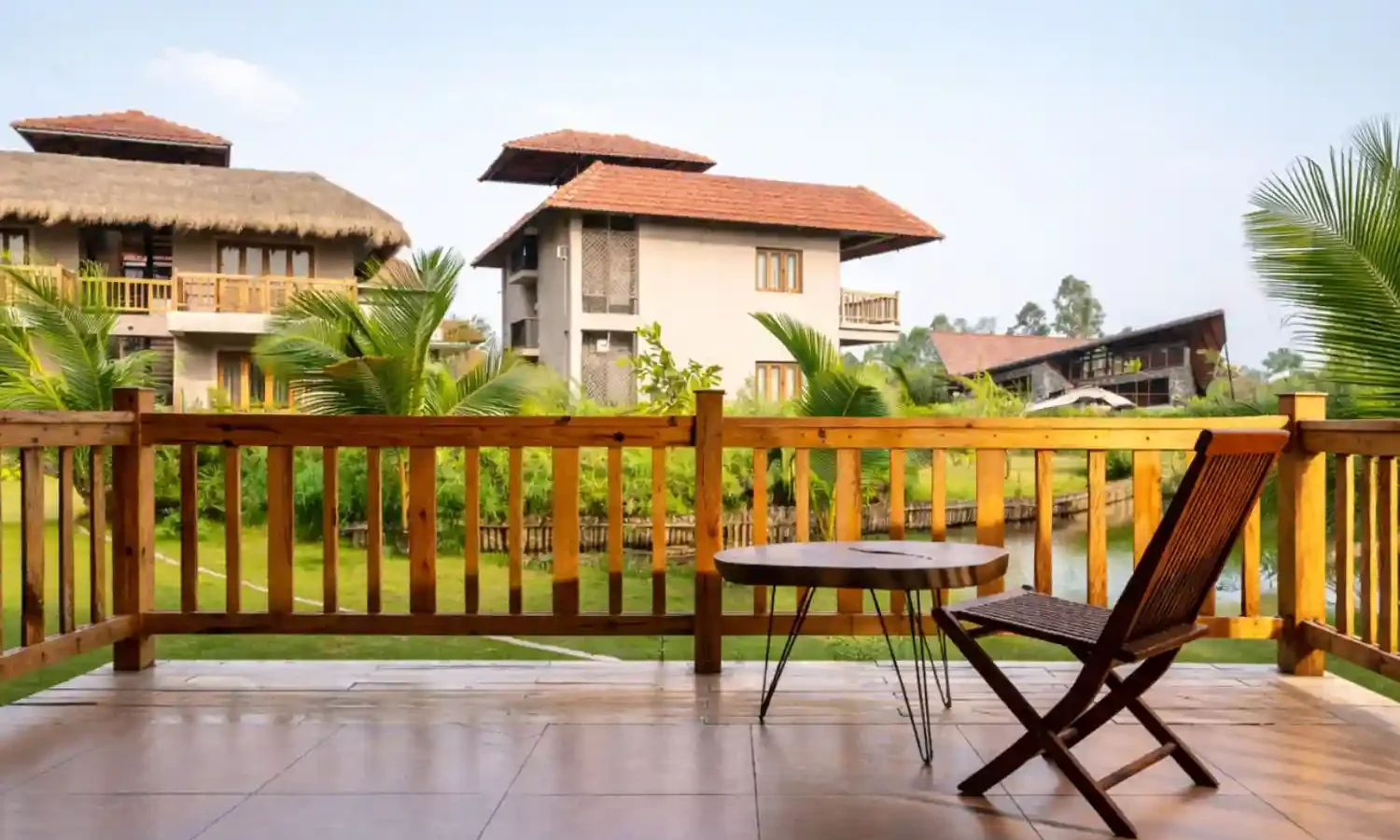 Hotel Sonar Bangla Sundarban Luxury Resort Balcony View Luxury balcony sitting area at Hotel Sonar Bangla Sundarban resort with garden and cottage view.